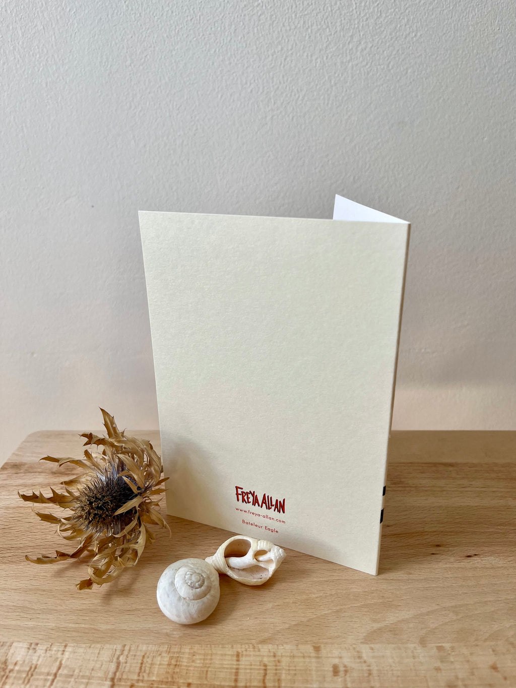 Bateleur Eagle greetings card -- back of a greeting card with 'Freya Allan' branding on a wooden surface with decorative elements.