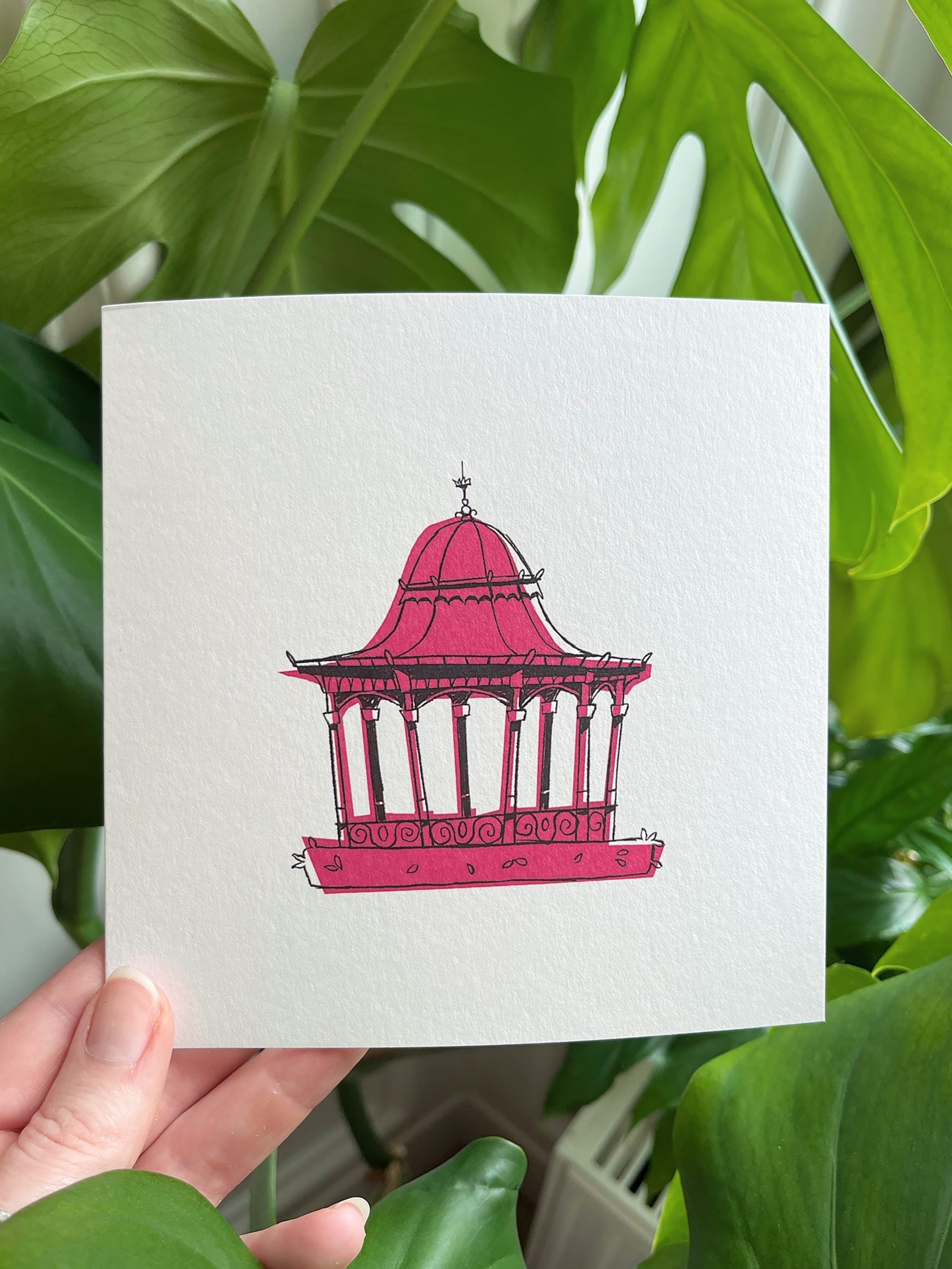 Dundee Bandstand greetings card -- card with  a pink bandstand design held in front of green leaves