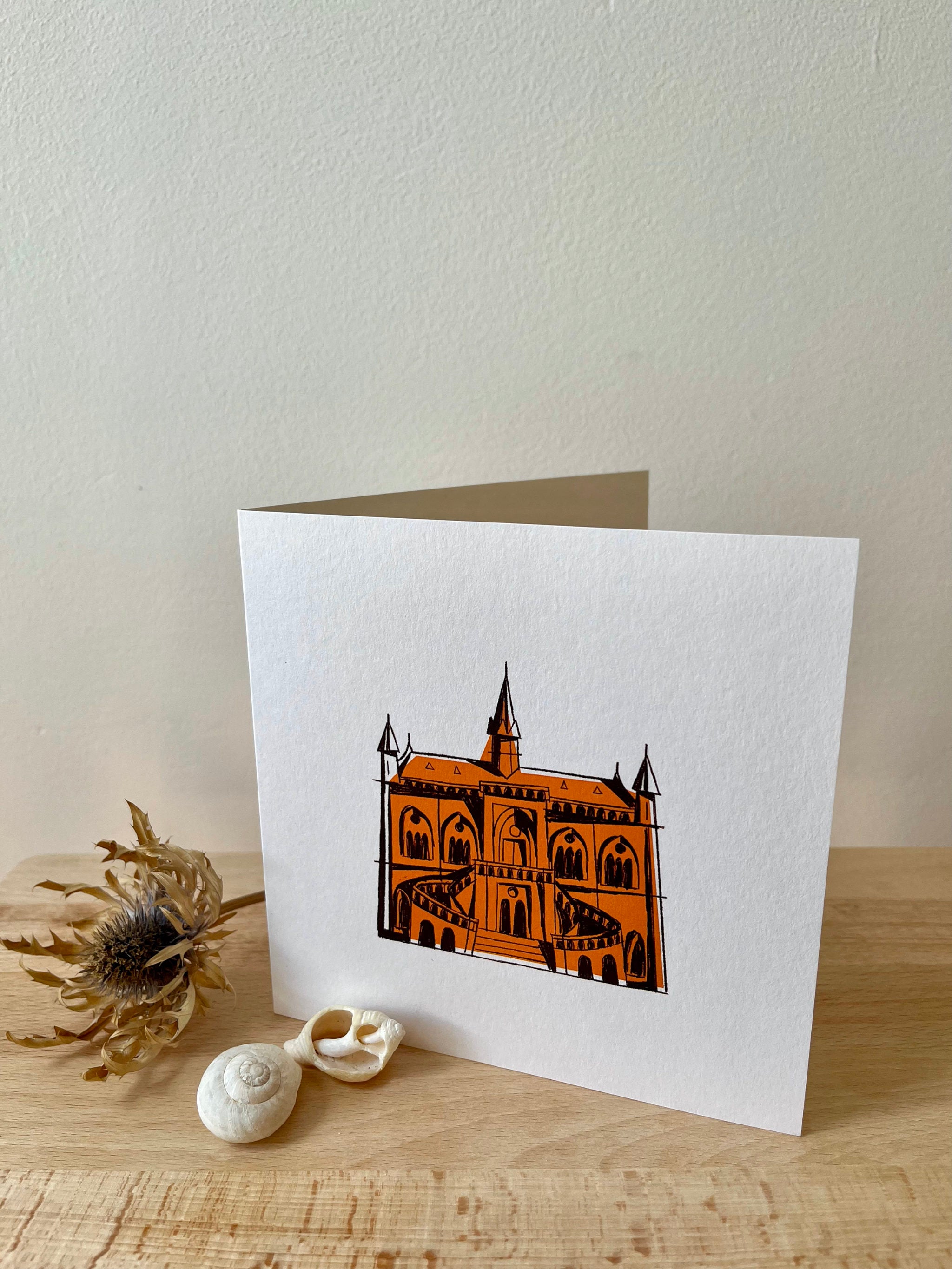 McManus Gallery greeting card -- greeting card with a 'castle' illustration on a wooden surface with seashells and a dried plant.