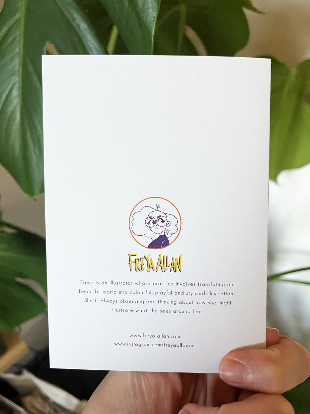 Game Changer greetings card -- card with Freya Allan's illustration and branding held by a hand with a plant in the background.