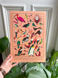 Birds print -- A3 colorful bird illustration print held by a hand with plants in the background.