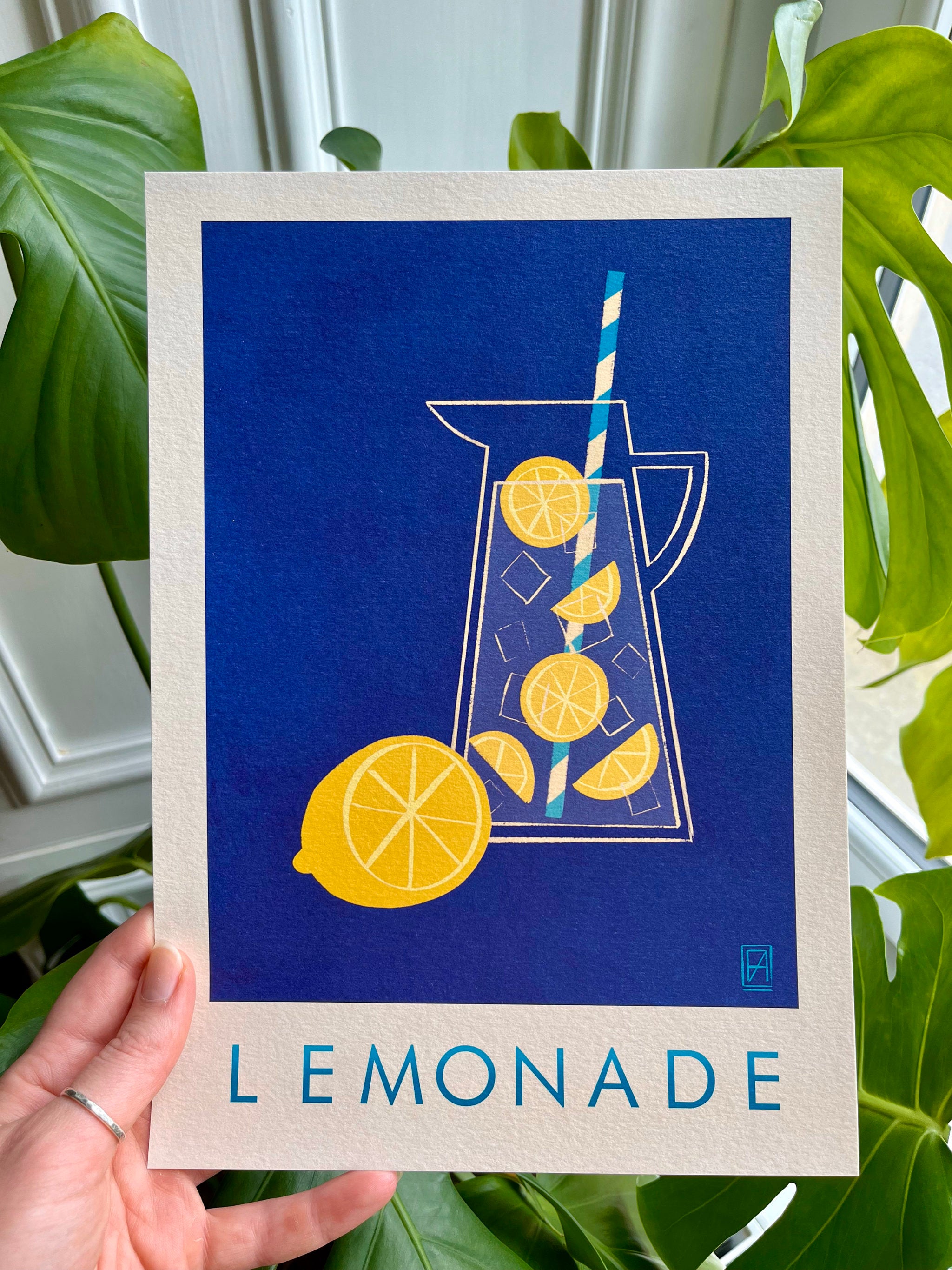 Lemonade print -- A4 print with a pitcher of lemonade design held by a hand against a leafy green background.