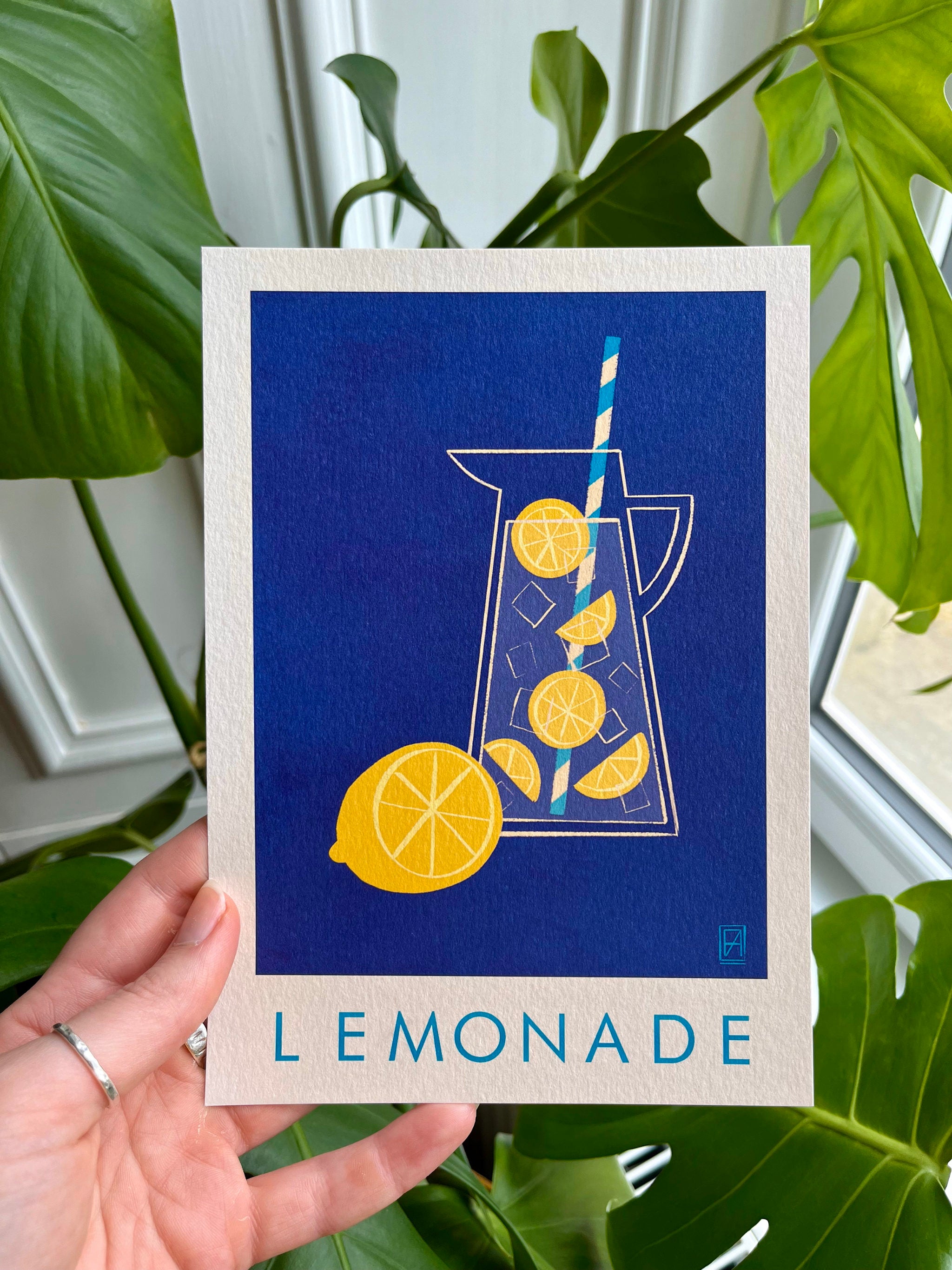 Lemonade print -- A5 print with a pitcher of lemonade design held by a hand against a leafy green background.