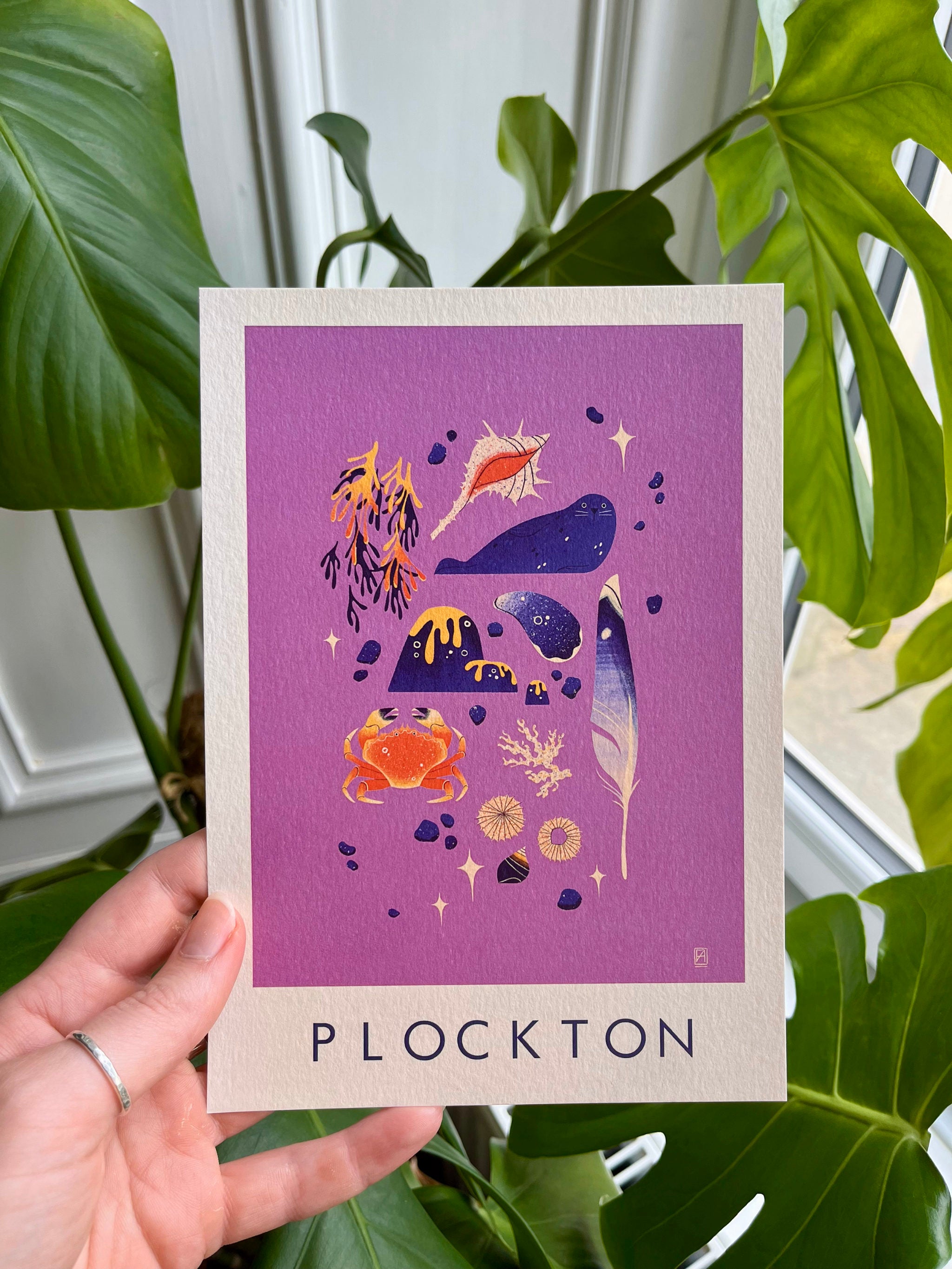 Plockton print -- A5 card with illustrations and 'Plockton' text held by a hand with plants in the background.