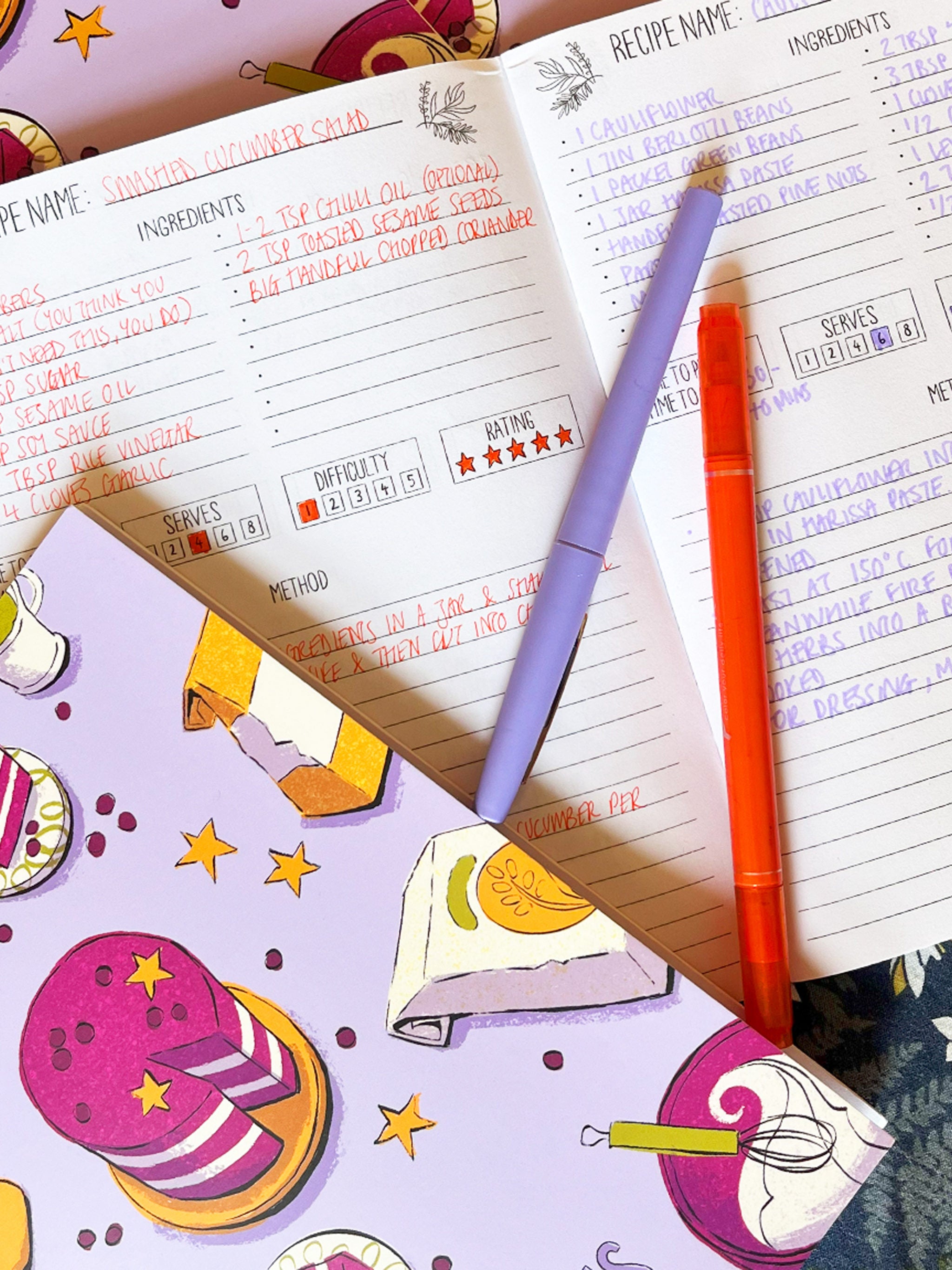 Recipe Journal -- open recipe book with two pens on a colorful background.