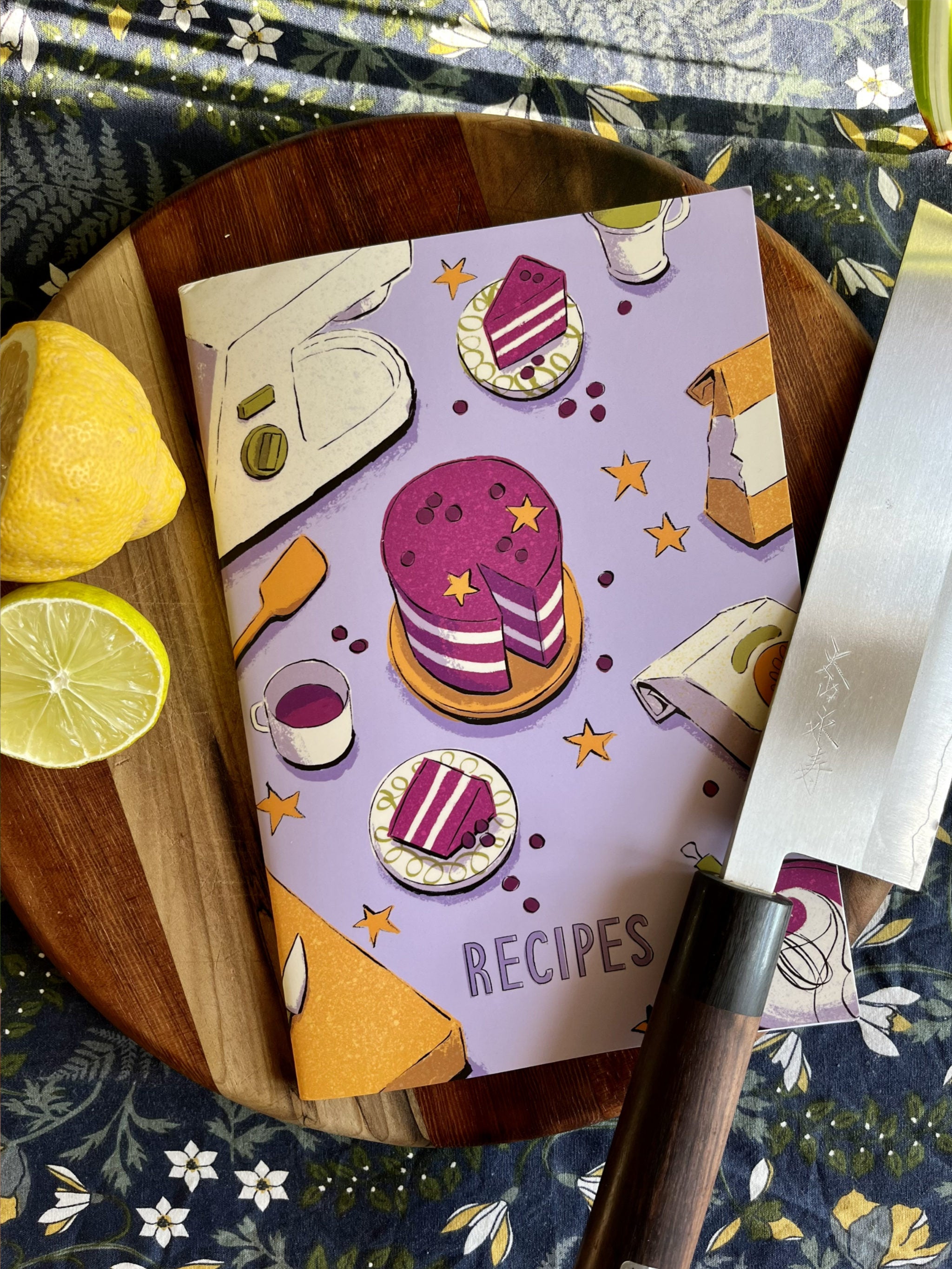 Recipe Journal -- cookbook with food illustrations on a wooden cutting board with lemons and a knife.